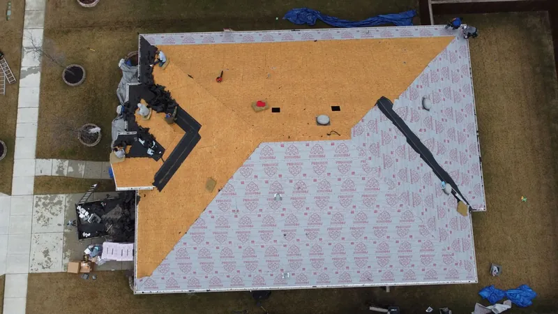 Drone view of the same roof mid replacement, decking exposed and underlayment going down